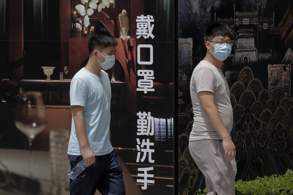 People pass a restaurant in Beijing displaying an ad saying “wear a mask and wash hands”. The Lancet has praised aspects of China’s response to the pandemic, including widespread use of masks. Photo: AP