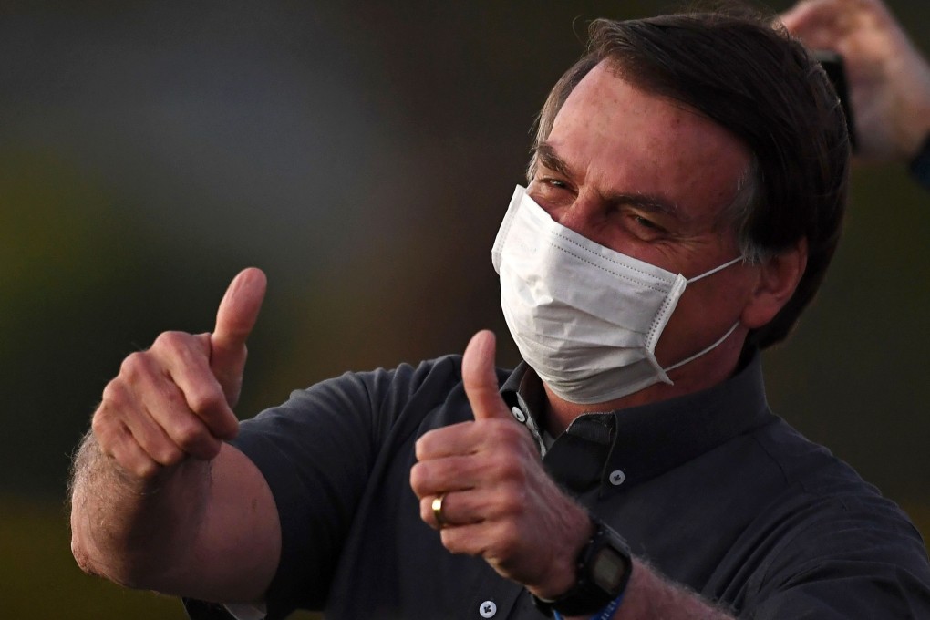Brazilian President Jair Bolsonaro gives the thumbs up to supporters from the Alvorada Palace in Brasilia. He said on Saturday he has recovered from Covid-19. Photo: AFP