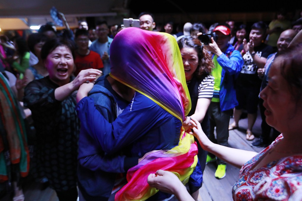 A gay couple kisses under a rainbow-coloured scarf during a party after a mass wedding organised by the Parents and Friends of Lesbians and Gays (PFLAG) China organisation on a cruise in the open seas en route to Sasebo, Japan, on June 15, 2017. About 800 members of the Chinese LGBT community and their parents spent four days on a cruise trip organised by the NGO. Photo: EPA