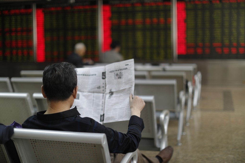 A Chinese investor reads a newspaper at a securities brokerage in Beijing. China added 1.55 million new stock traders in June. Photo: EPA-EFE