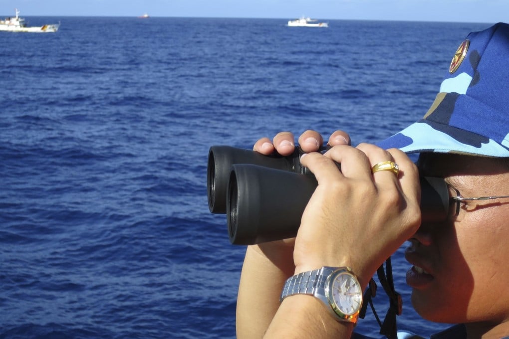 A Vietnamese coastguard crewman looks out to sea as Chinese vessels are seen in the distance. The US has promised to assist Vietnam fend off illegal intrusion, but Hanoi remains cautious. Photo: Reuters