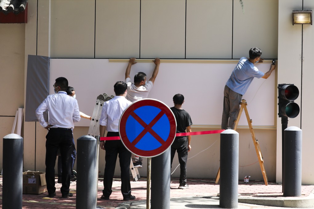 Workers start to cover the name of the US Consulate General in Chengdu with white board on July 27, after Beijing closed it in retaliation against the Houston closure. Photo: Simon Song