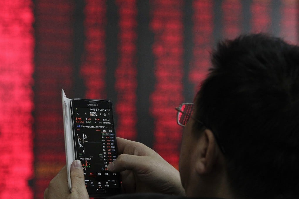 A man checks stock prices through his smartphone at a brokerage house in Beijing on Wednesday, Jan. 9, 2019. Contrary to global conventions, China denotes gains and advances in red and represents losses and declines in green. Photo: AP Photo