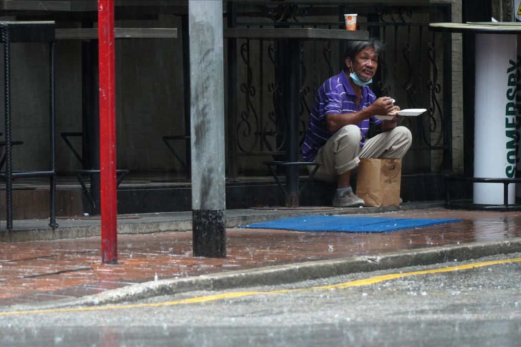 A man takes shelter from the rain to eat his takeaway lunch in Hong Kong’s Tsim Sha Tsui shopping district on Wednesday, amid a short-lived ban on restaurant dining meant to stem a third wave of Covid-19 infections. Photo: Sam Tsang