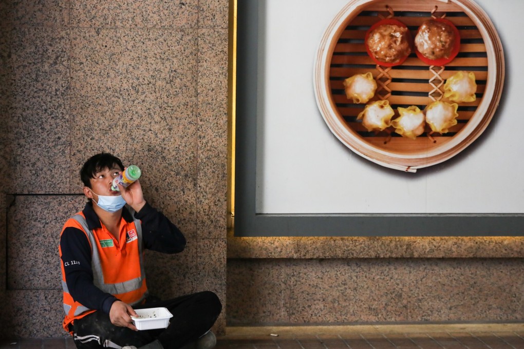 A worker eats lunch on the side of the road in Wan Chai on July 30, a day after the government’s ban on restaurants offering dine-in services came into force. Photo: K. Y. Cheng