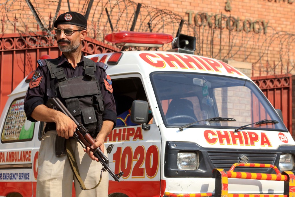 A police officer stands guard as an ambulance transports the body of Tahir Ahmad Nasim, who was shot dead in Peshawar, Pakistan on Wednesday. Photo: EPA-EFE