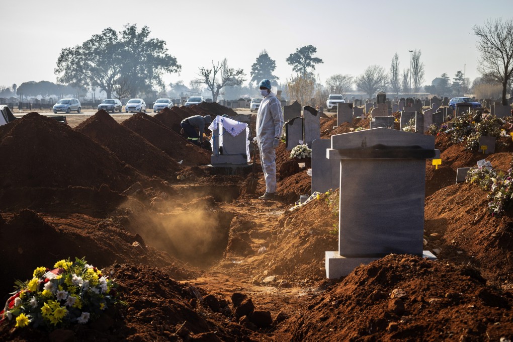 A family member wearing a full PPE suite looks on after the funeral of an elderly relative who died as a result of Covid-19 in Johannesburg. Photo: EPA-EFE