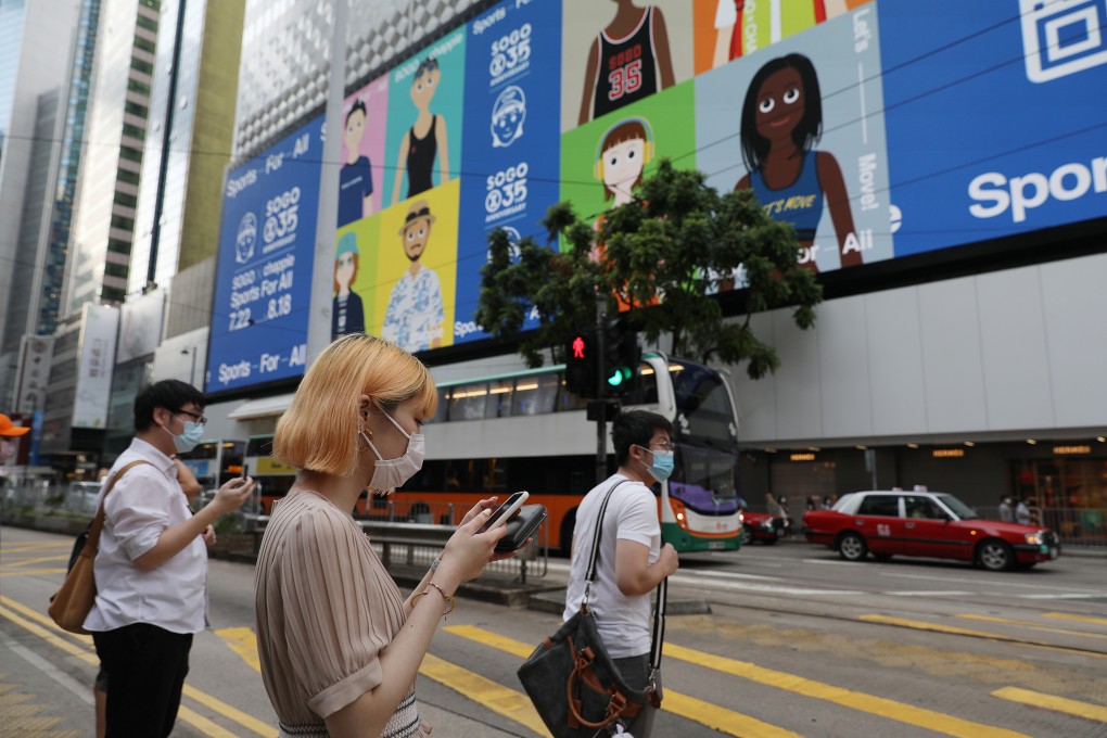 Pedestrians in face masks wait to cross the road in Causeway Bay on July 29, as compulsory mask-wearing rules to cover all public areas came into effect as part of stricter measures against the third wave of coronavirus infections. Photo: Nora Tam