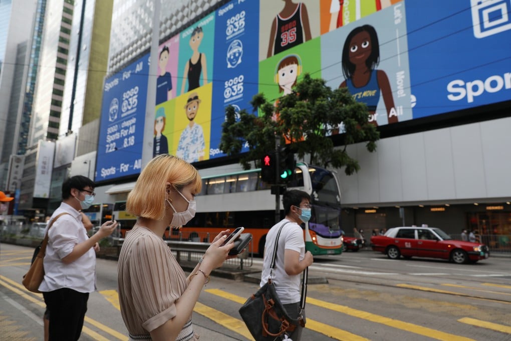 Pedestrians in face masks wait to cross the road in Causeway Bay on July 29, as compulsory mask-wearing rules to cover all public areas came into effect as part of stricter measures against the third wave of coronavirus infections. Photo: Nora Tam