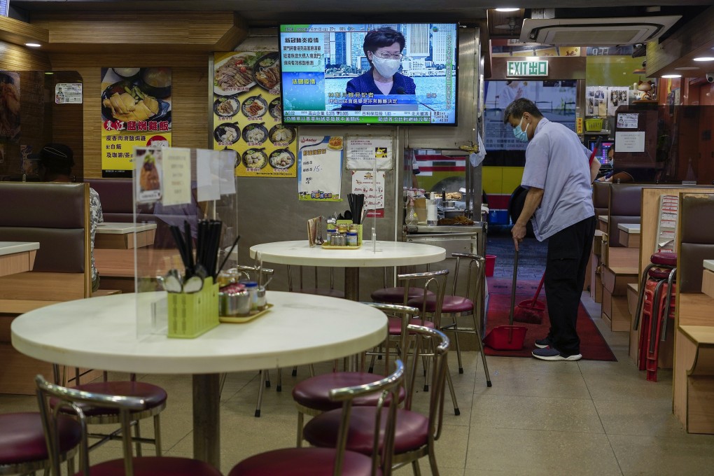 A restaurant employee cleans the floor as a television broadcasts Hong Kong Chief Executive Carrie Lam explaining her decision to postpone the Legco elections. Photo: AP