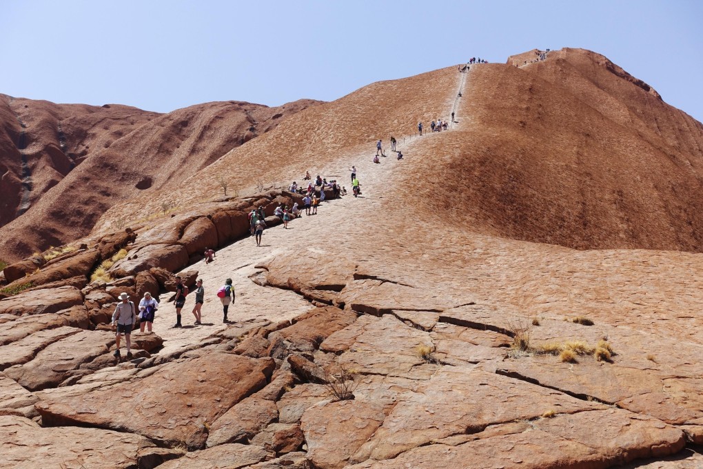 People climb Uluru in Australia’s Northern Territory in October last year. The famous monolith was closed to visitors after a local indigenous group said interstate tourists travelling there during the coronavirus crisis might spread Covid-19 to vulnerable indigenous residents. Photo: Getty Images