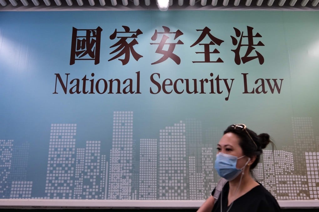A woman walks past a poster for the National Security Law in Hong Kong in July. Photo: AFP