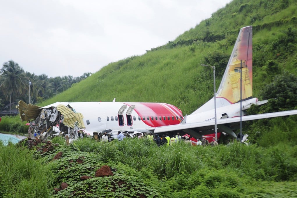 Officials at the scene after an Air India Express flight skidded off a runway while landing in Kozhikode, Kerala state, India, killing at least 18 people. Photo: AP