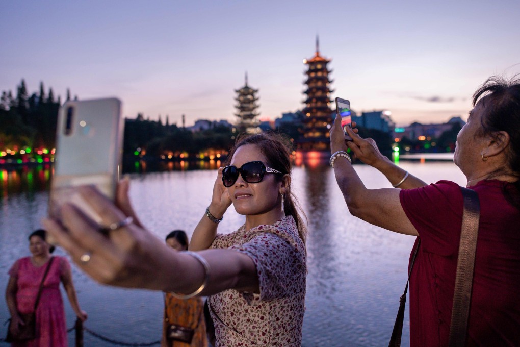 Visitors to Guilin’s “Four Lakes” scenic area take photos of the sunset on August 8. China’s July trade data showed a larger-than-expected bounce, but it will take a while for companies and consumers to return to full-on spending sprees. Photo: AFP