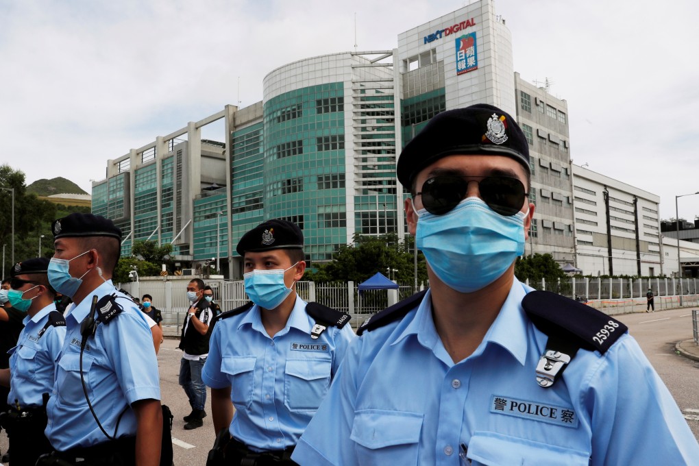 Police officers stand guard outside the headquarters of Apple Daily and Next Media. Photo: Reuters