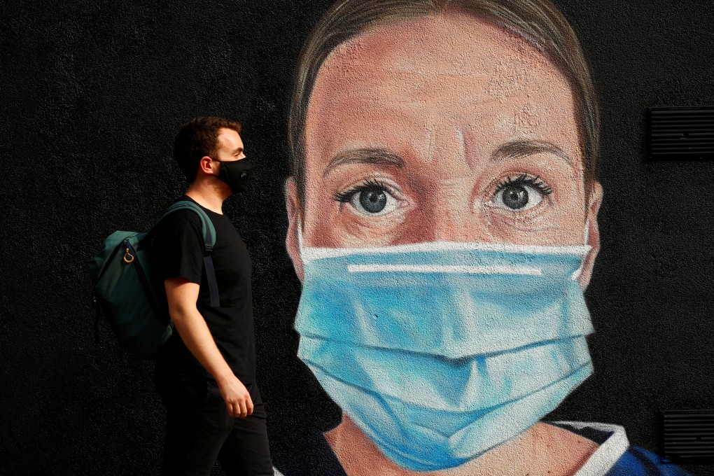 A man wearing a face mask walks by a mural depicting a medical worker in Manchester, Britain on Monday. Photo: Reuters