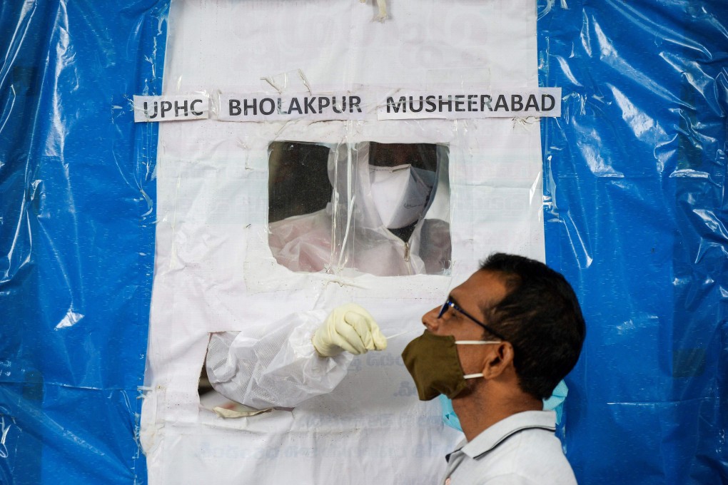 A health worker collects a swab from a resident at a makeshift coronavirus testing booth in Hyderabad on Monday. Photo: AFP