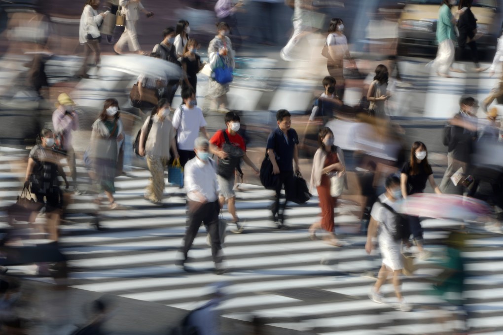 Pedestrians wearing face masks walk across a street in Tokyo earlier this month. Mask-wearing has been commonplace in Japan for years. Photo: EPA