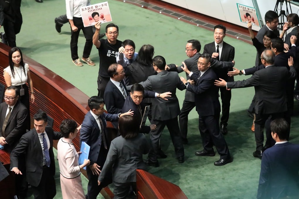 Legco security guards holds back a group of pan-democratic lawmakers as they attempt to surround Hong Kong Chief Executive Carrie Lam Cheng Yuet-ngor (bottom left holding folder) as she leaves the Legislative Council chamber on October 16. Lam was unable to deliver the 2019 policy address speech as lawmakers constantly interrupted her with shouts and protests. Photo: K.Y. Cheng
