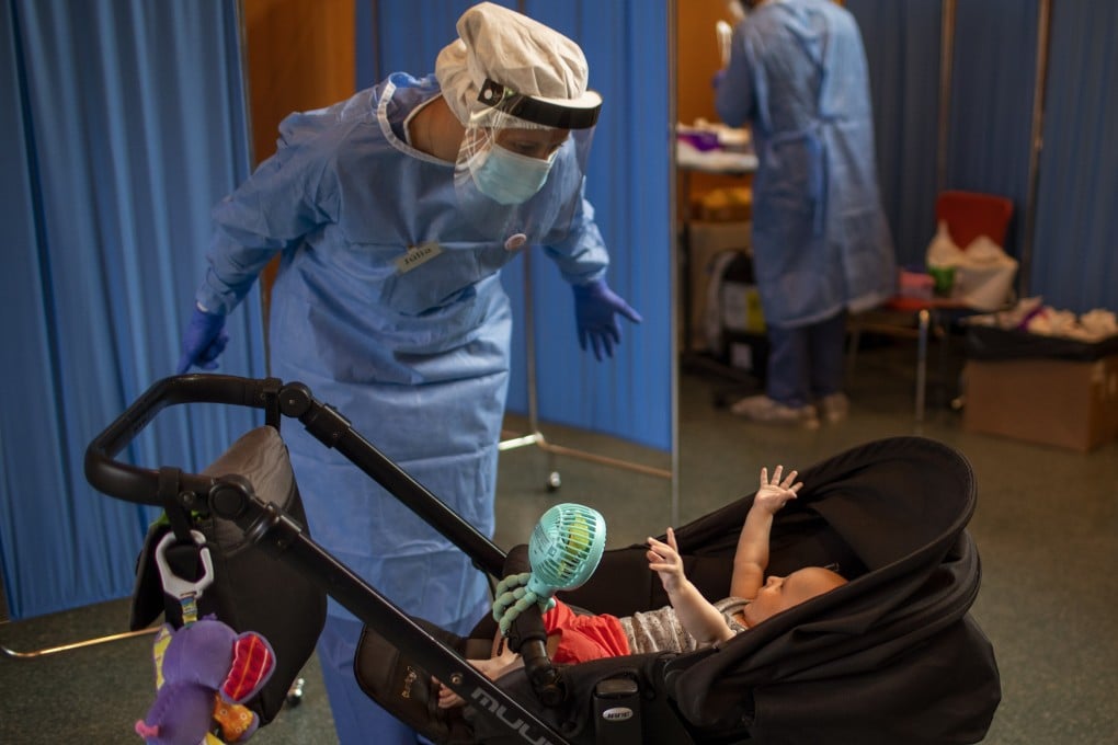 A volunteer plays with an infant whose father was getting tested for the coronavirus at Vilafranca del Penedes in Barcelona province, Spain. Photo: AP