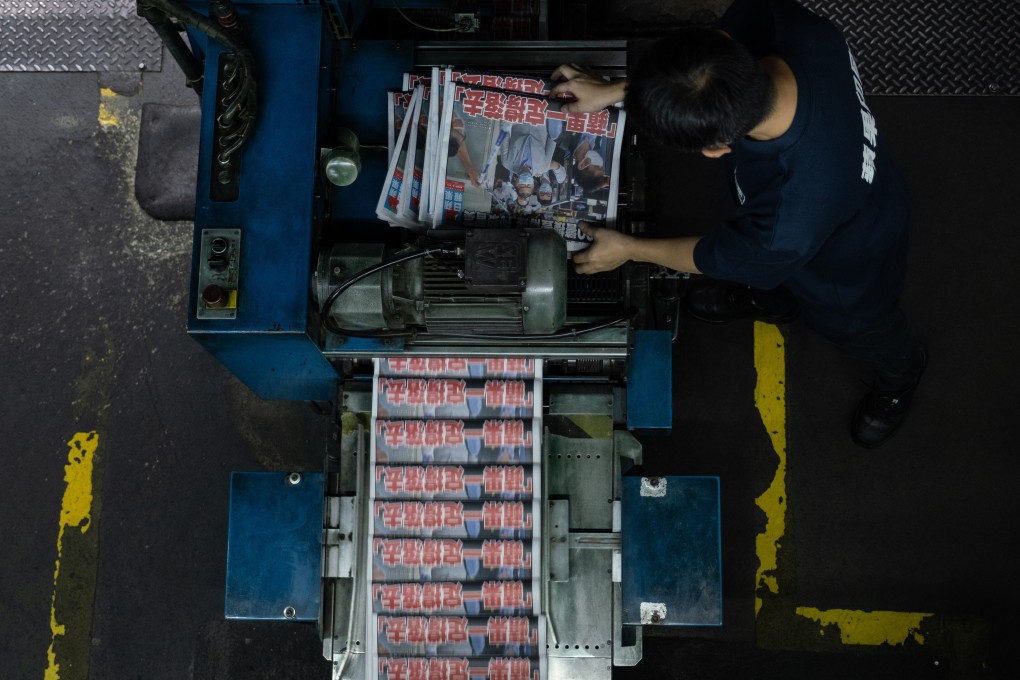 Employees wearing protective masks inspect the print quality of pages of the Apple Daily newspaper, published by Next Digital Ltd., at the company's printing facility in Hong Kong. Photo: Bloomberg