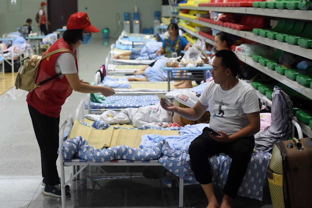 A volunteer gives a safety instruction booklet to a villager at a temporary shelter in the No 168 Middle School in Hefei, Anhui province, in late July. Photo: Xinhua