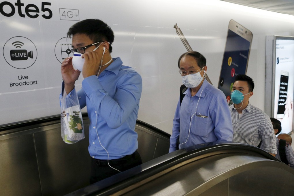 Singaporean officer workers wearing masks leave a train station during the morning commute. Photo: Reuters