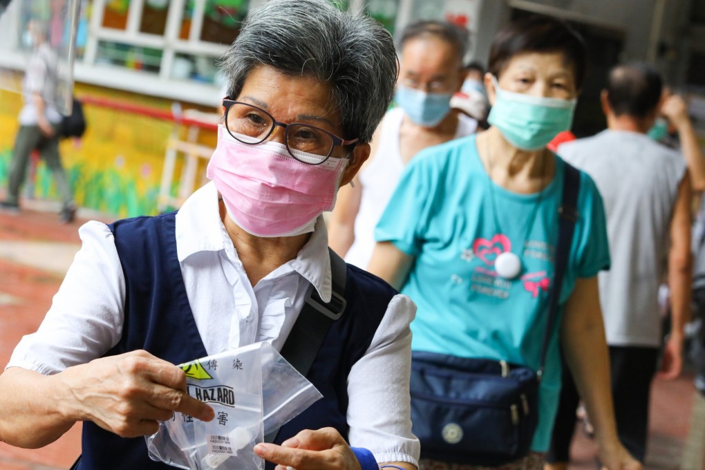 Health department staff give out Covid-19 testing packs on an estate in Kowloon. Photo: Dickson Lee
