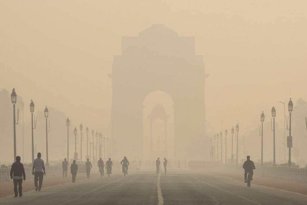Pedestrians walk along New Delhi’s Rajpath boulevard in November 2019 as the India Gate monument stands shrouded in smog. Photo: Bloomberg