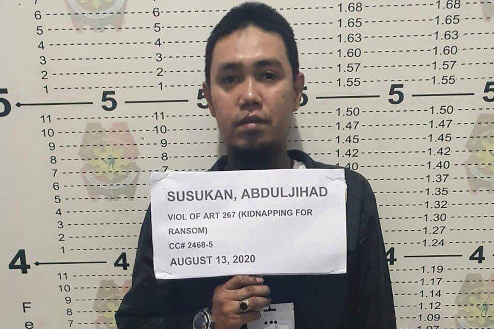 In this photo provided by the Philippine National Police-Public Information Office, Abu Sayyaf commander Anduljihad Susukan poses for a picture at the Davao City Police Station in Davao province, southern Philippines on Thursday Aug. 13, 2020. Susukan, a leading terror suspect who has been linked to beheadings of hostages including two Canadians and a Malaysian, has surrendered after being wounded in battle, officials said Friday. (Philippine National Police PIO via AP)