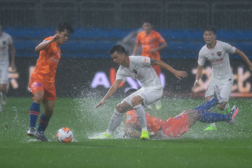 Water sprays up from the pitch in the game between Shandong Luneng and Shenzhen in Dalian. Photo: Xinhua