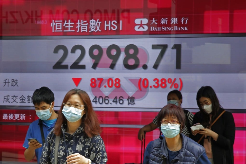 People walk past an electronic board showing the Hong Kong share index outside a local bank in Hong Kong. Photo: AP