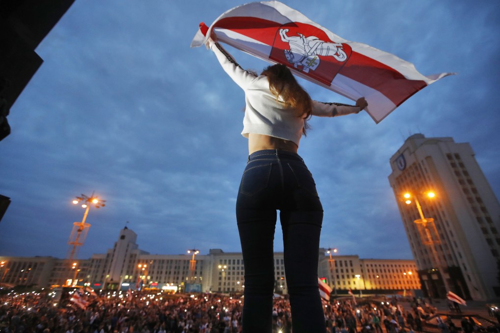 An opposition supporter holds an old Belarusian national flag during a protest in front of the government building at Independent Square in Minsk on Thursday. Photo: AP