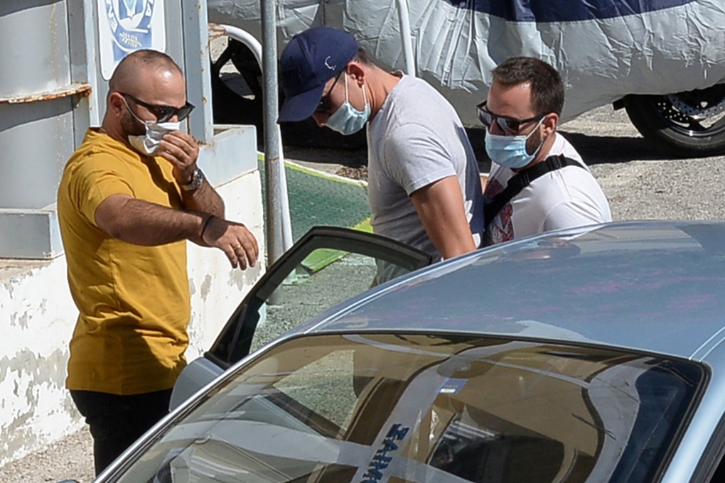 A man with a blue cap, believed to be Manchester United captain Harry Maguire, is escorted by plain-clothes police officers to the police station of the island of Syros, Greece, Photo: Reuters