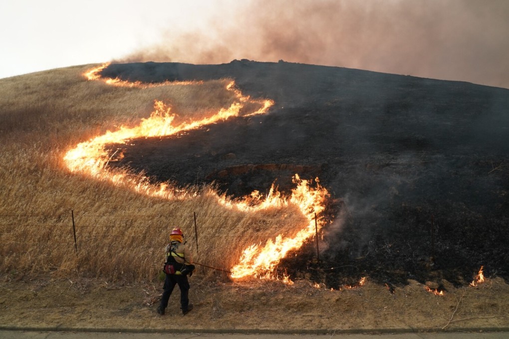 A firefighter rakes dry vegetation to the backfire during the Lightning Complex fire on August 19 in Vacaville, California. Photo: SIPA USA/TNS