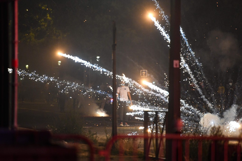 A man is pictured as tear gas canisters explode around him following a night of violence on the streets of Paris after PSG’s loss to Bayern Munich. Photo: AFP