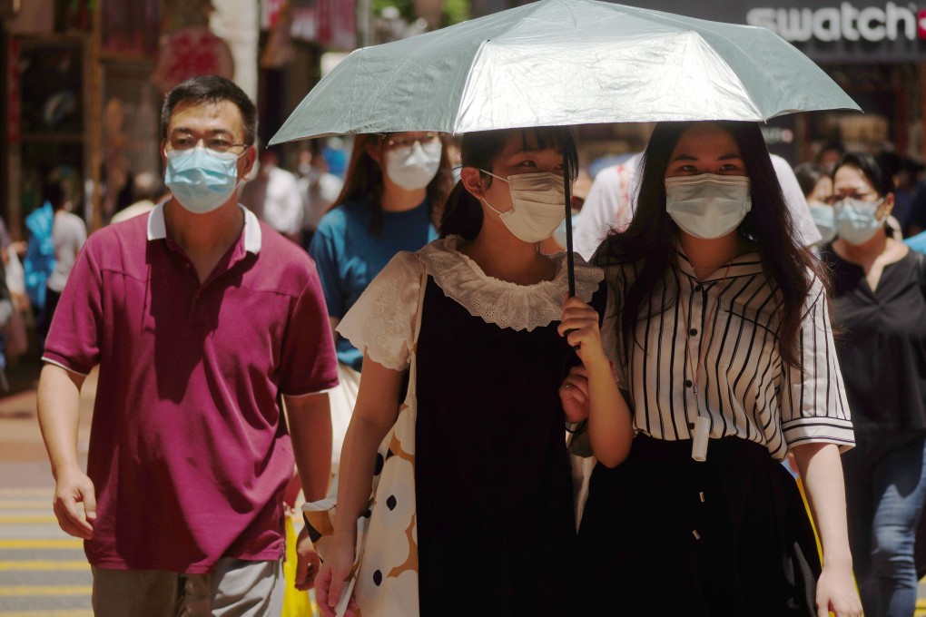 Pedestrians use an umbrella to shield themselves from the sun as they walk down the street on Monday. Photo: Sam Tsang
