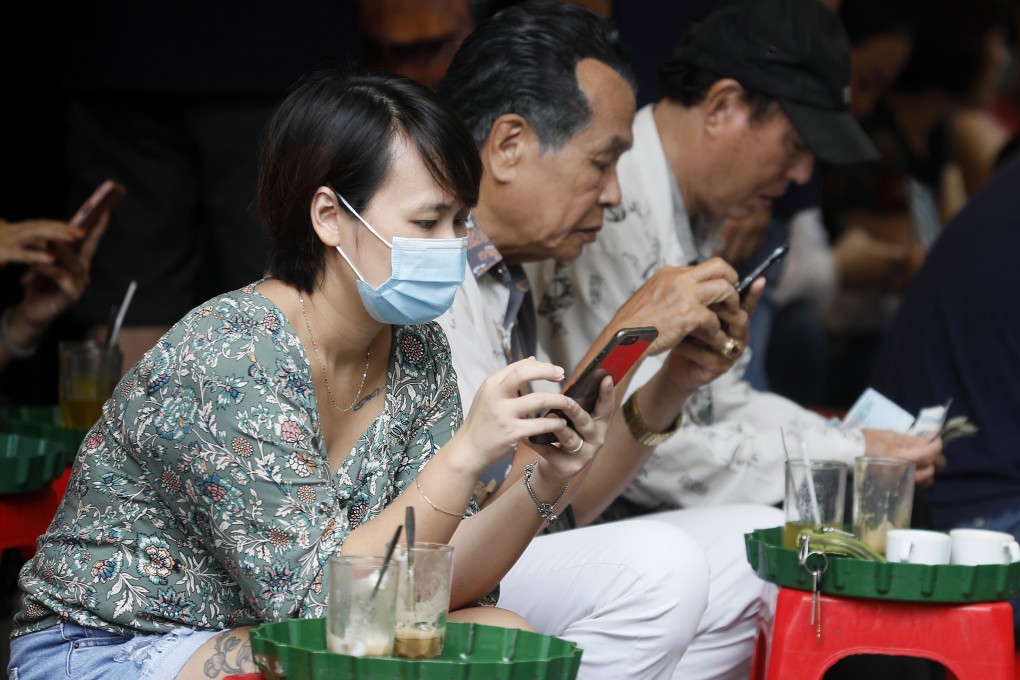A woman checks her mobile phone at a street cafe in Hanoi. Photo: EPA-EFE
