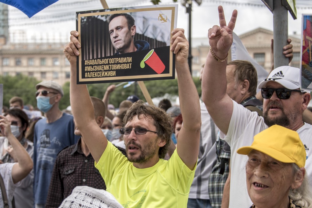 A man holds a poster with a portrait of Alexei Navalny reading “Navalny was poisoned, we know who is to blame, Alexei you must live” during a protest in Khabarovsk, Russia on Saturday. Photo: AP