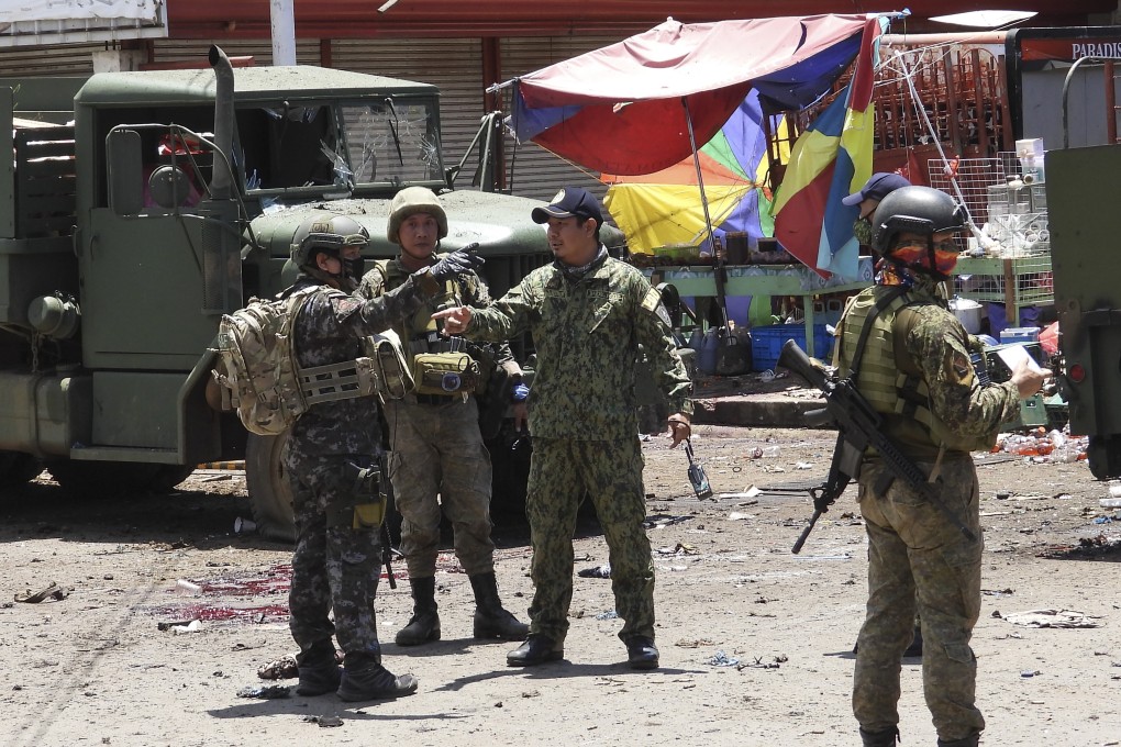 Police and military talk at the site of an explosion in the town of Jolo, Sulu province. The country’s army chief believes reimposing martial law in Sulu could help isolate and track down the Abu Sayyaf network. Photo: AP