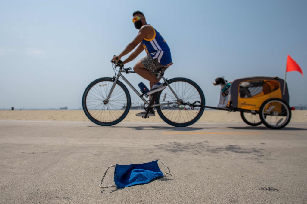 A man rides his bike near a discarded face mask in Long Beach, California. Photo: AFP
