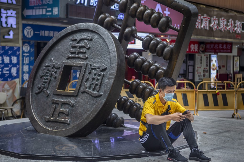 A man uses his cellphone as he sits next to a sculpture representing the renminbi and an abacus in Guangzhou, China, on May 14. China has launched a trial of a new state-run digital currency in four cities: Shenzhen, Suzhou, Chengdu and Xiongan. Photo: EPA-EFE