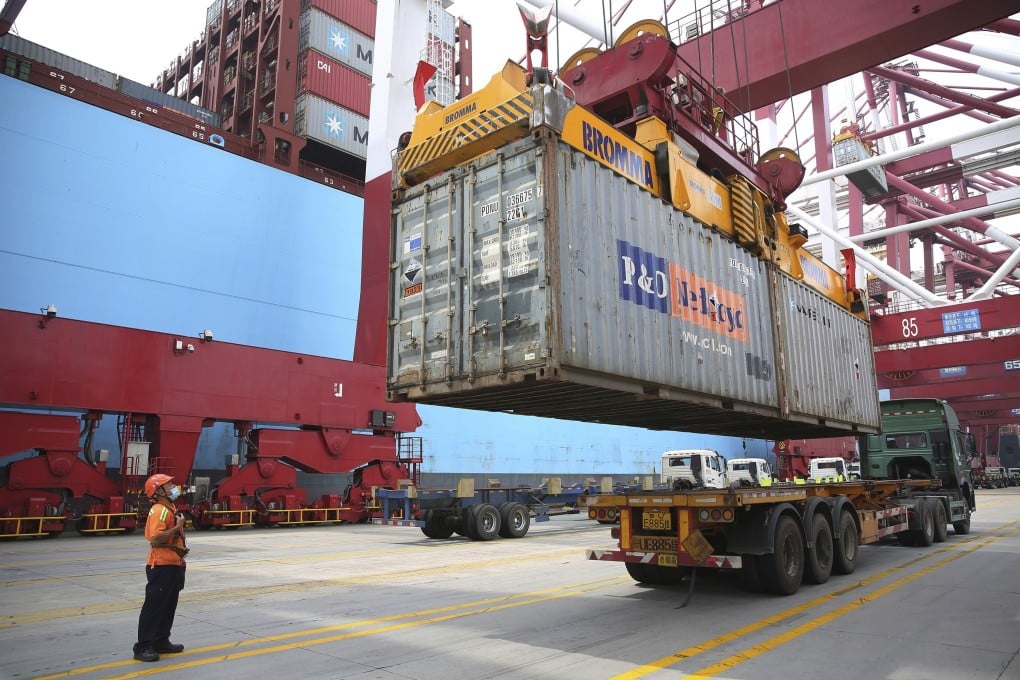 A worker wearing a mask guides the loading of a shipping container at a port in Qingdao, China. Photo: AP
