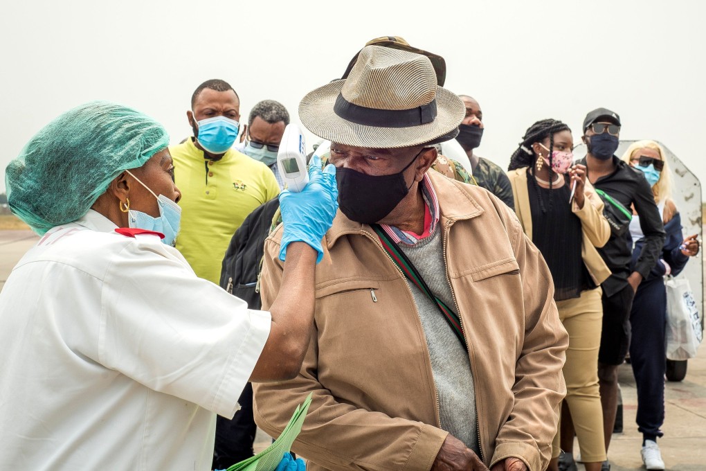 An airport worker takes the temperature of a passenger arriving at N'djili International Airport in Kinshasa on August 15. Congo’s multiple battles with Ebola have helped to prepare it for the fight against Covid-19. Photo: AFP