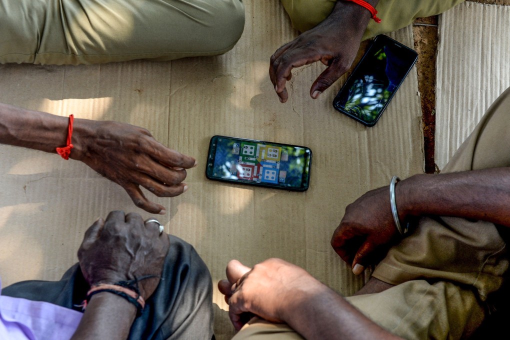 Drivers play a game on a mobile phone as they wait for customers at the prepaid taxi stand at Chennai International Airport in Chennai on March 19, 2020. Photo: AFP