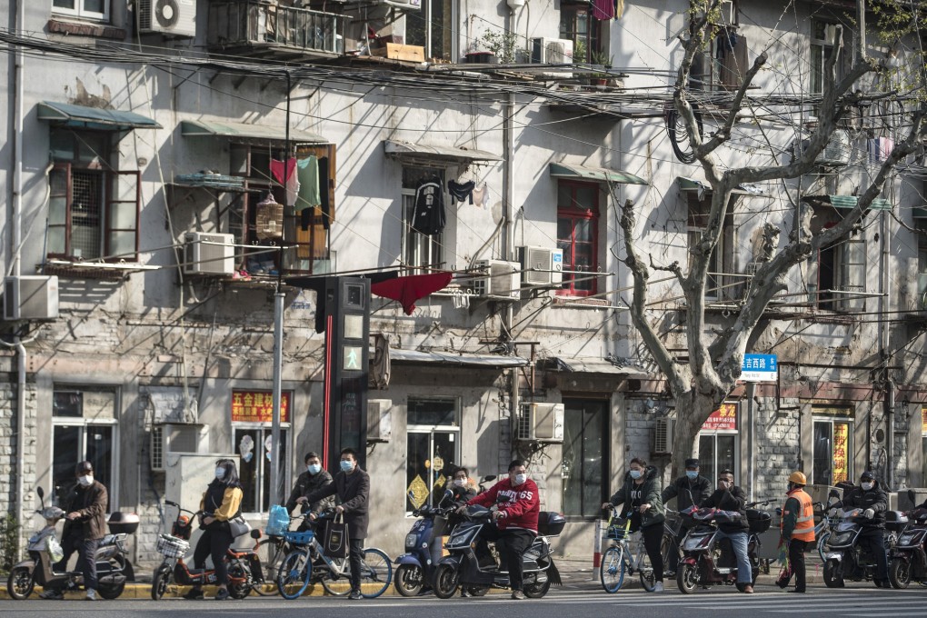 Moped riders and cyclists wearing masks wait at a traffic light in Shanghai on April 2. Photo: Bloomberg
