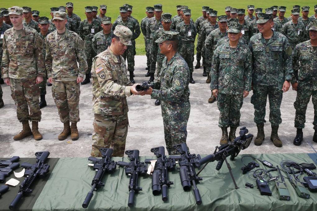 A Philippine marine receives an M4 rifle from a US colonel during a handover of brand new military weapons and other equipment in Taguig city, east of Manila. Photo: AP