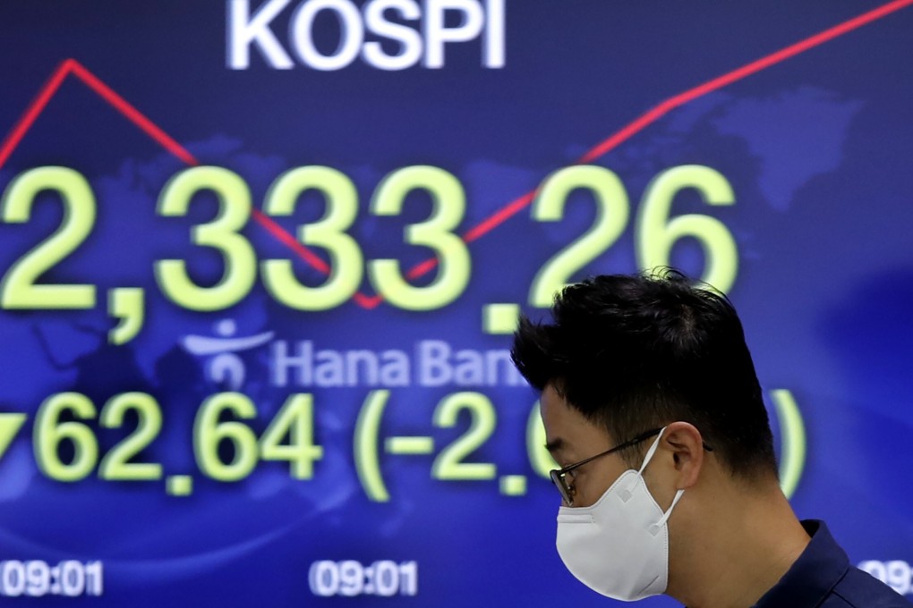 A currency trader walks by the screen showing the Korea Composite Stock Price Index at the foreign exchange dealing room in Seoul. Photo: AP