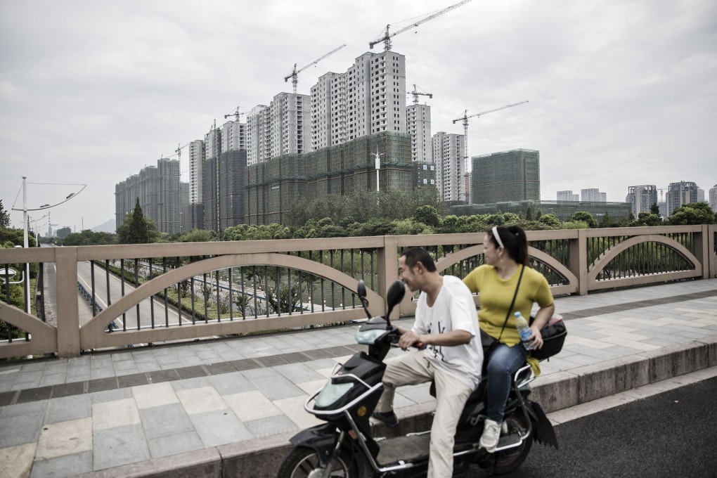 People ride a motorcycle through an overpass as cranes stand at buildings under construction in Hangzhou, China, in 2016. Photo: Bloomberg