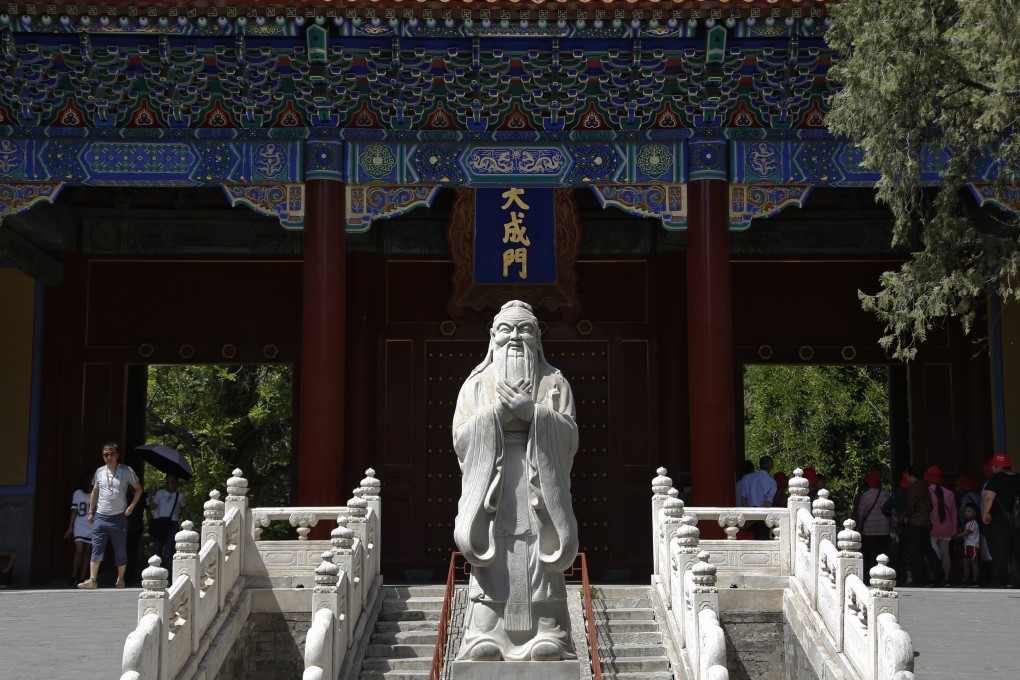 Tourists walk by a statue of ancient Chinese philosopher Confucius at the Confucius Temple in Beijing. Photo: AP